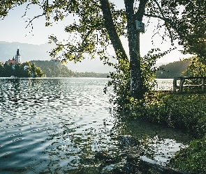 Wyspa Blejski Otok, Promienie słońca, Słowenia, Jezioro Bled, Kościół Zwiastowania Marii Panny, Góry Alpy Julijskie, Ławka, Drzewa