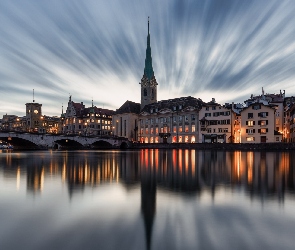 Domy, Niebo, Szwajcaria, Most Munsterbrucke, Chmury, Światła, Zurych, Wieczór, Kościół Fraumunster, Rzeka, Limmat